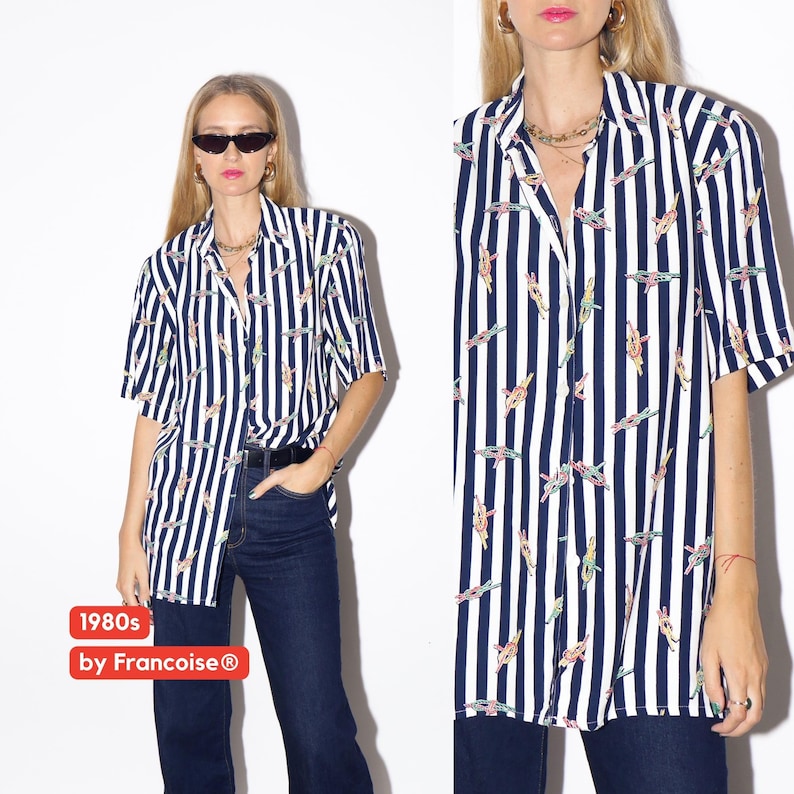 May include: A short-sleeved button-down shirt with vertical navy blue and white stripes. The shirt features a pattern of colorful, abstract shapes. The text "1980s by Francoise&reg;" is visible in the lower left corner.