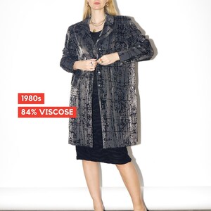 May include: A vintage, long, gray and black patterned coat with a button closure. The coat is worn over a black dress and paired with black heels. The text "1980s" and "84% VISCOSE" are visible.