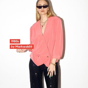 May include: A coral-colored wrap blouse with gold buttons, paired with black sequin pants. The image includes the text "1980s by Markwald®". The outfit is accessorized with sunglasses, gold jewelry, and rings.