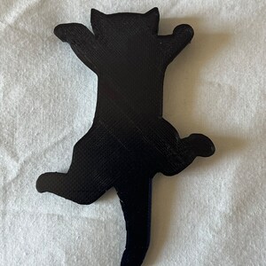 Op de afbeelding: Een zwart 3D-geprint kattenbeeldje in een speelse pose met uitgestrekte poten en een opgerolde staart.