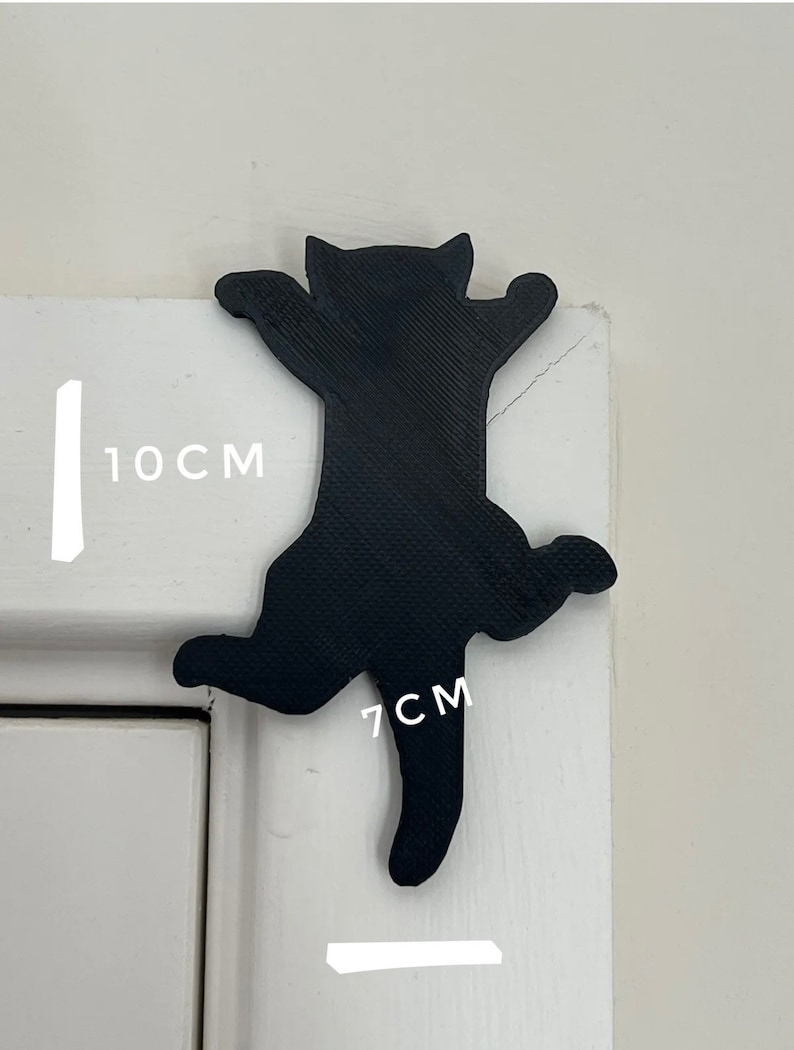 Op de afbeelding: Zwarte kat silhouet wanddecoratie, 10 cm hoog en 7 cm breed. De kat is in een klimhouding met uitgestrekte poten.