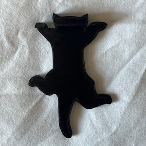 Op de afbeelding: Een zwart 3D-geprint kattenbeeldje in een speelse pose met uitgestrekte poten en een achterovergekanteld hoofd.