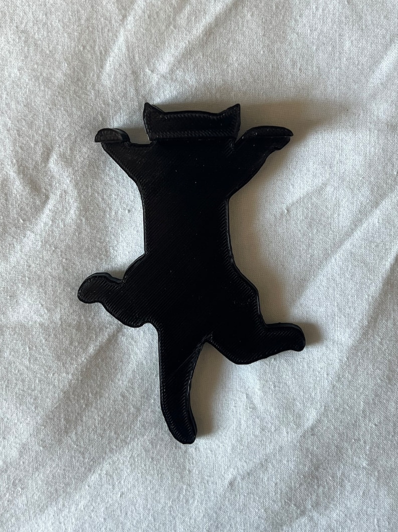 Op de afbeelding: Een zwart 3D-geprint kattenbeeldje in een speelse pose met uitgestrekte poten en een achterovergekanteld hoofd.