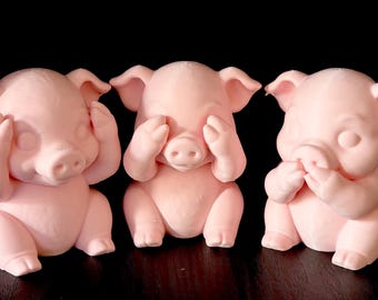 May include: Three light pink pig figurines arranged in a row. The first pig covers its ears with its hooves, the second pig covers its eyes with its hooves, and the third pig covers its mouth with its hooves. Each pig has a smooth matte finish.