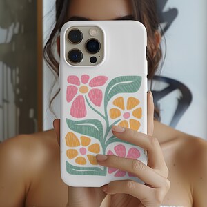 May include: White iPhone case with a floral design. The design features pink, yellow, and green flowers with a white background.