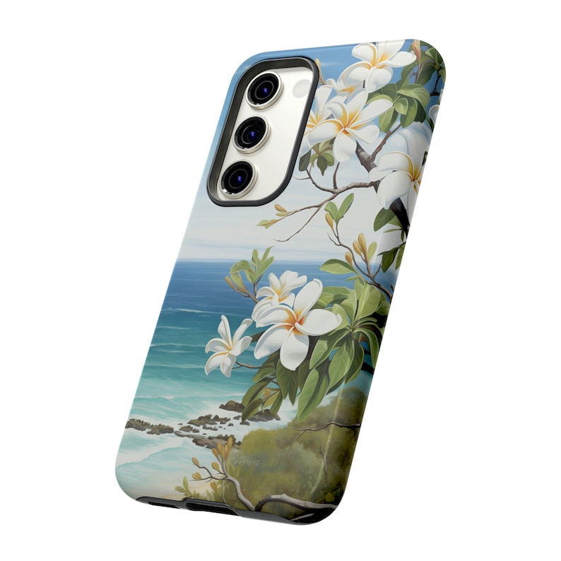 Pu&ograve; includere: Una custodia per telefono con un design floreale con fiori bianchi e foglie verdi su uno sfondo di oceano blu e cielo.
