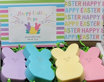 May include: A gift box filled with four pastel-colored bunny-shaped soaps. The soaps are lavender, blue, yellow, and pink. The box is decorated with a label that says "Happy Easter Peeps" and "Handcrafted Soap, Net wt 6 oz".