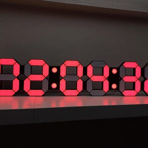 May include: A red LED digital clock displaying the time 8:88:88. The clock is made up of individual segments that light up to form the numbers.