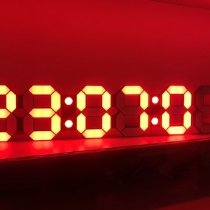 Può includere: Un orologio digitale a LED rosso che mostra l'ora 23:08:08. L'orologio è composto da segmenti LED individuali che si illuminano per formare i numeri.