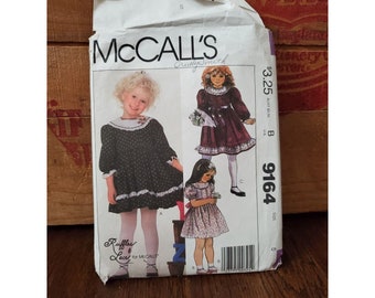 May include: A McCall's sewing pattern for a girl's dress. The pattern is for sizes 4-6 and includes three different styles. The pattern is called "Ruffle Lace for McCall's" and the pattern number is 9164.