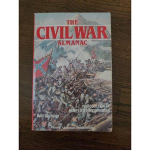 Puede incluir: Libro "The Civil War Almanac" con una ilustración de batalla en la portada. El título está en letras rojas, con soldados y banderas. También se lee "Totalmente ilustrado" y el nombre de la editorial.
