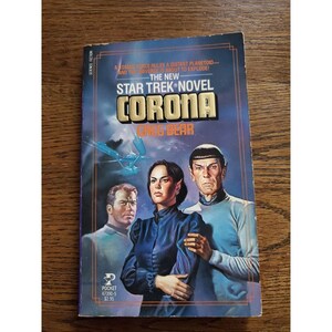 May include: A vintage paperback book titled "Corona" by Greg Bear, part of the Star Trek novel series. The cover features illustrations of characters and a spaceship against a blue and purple background. The book is published by Pocket Books.