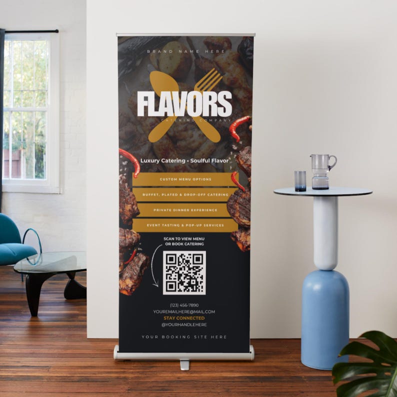 May include: A catering company's roll-up banner, displaying the name "FLAVORS" in white with a gold spoon and fork logo. The banner advertises catering services, a QR code for menu access, and contact details for potential clients.