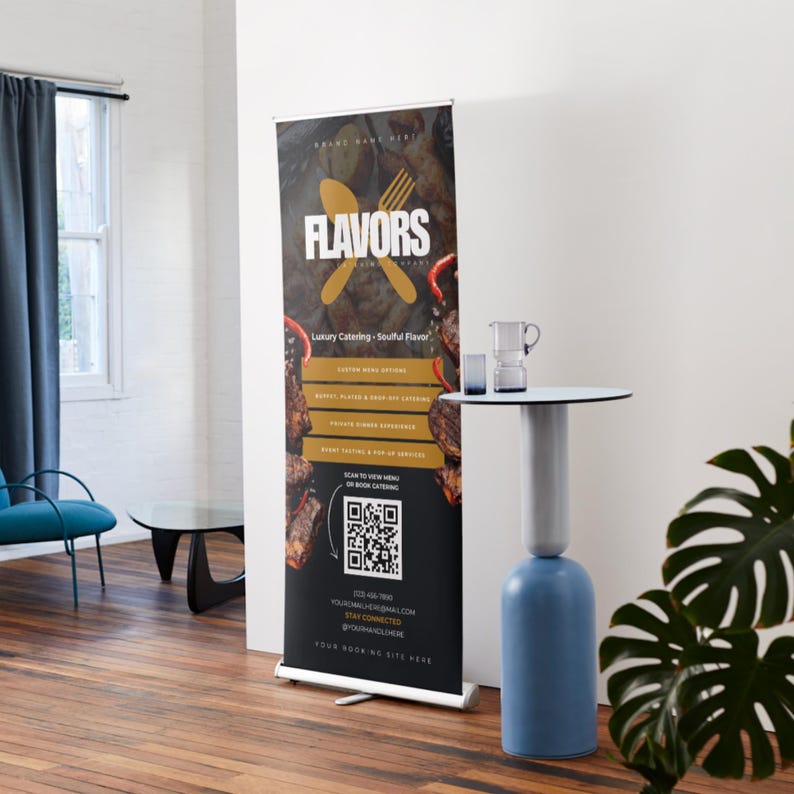 May include: A black and gold pull-up banner with the word "FLAVORS" in white. The banner promotes luxury catering services, featuring a QR code and contact details. A modern, two-tone table and a potted plant are in the foreground.