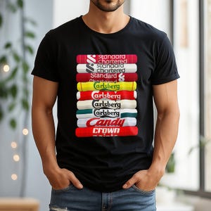 May include: Black t-shirt with a stacked design of logos and text, including "Standard Chartered", "Carlsberg", and "Candy Crown". The logos are in various colours. The shirt has a crew neck.