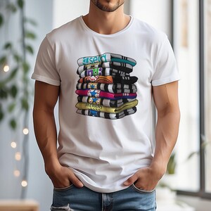 May include: White t-shirt featuring a stack of colorful scarves with various designs and text. The scarves are in shades of blue, black, yellow, pink, and orange. The text on the scarves includes the words "Kisel", "188", and "MCEWANS".