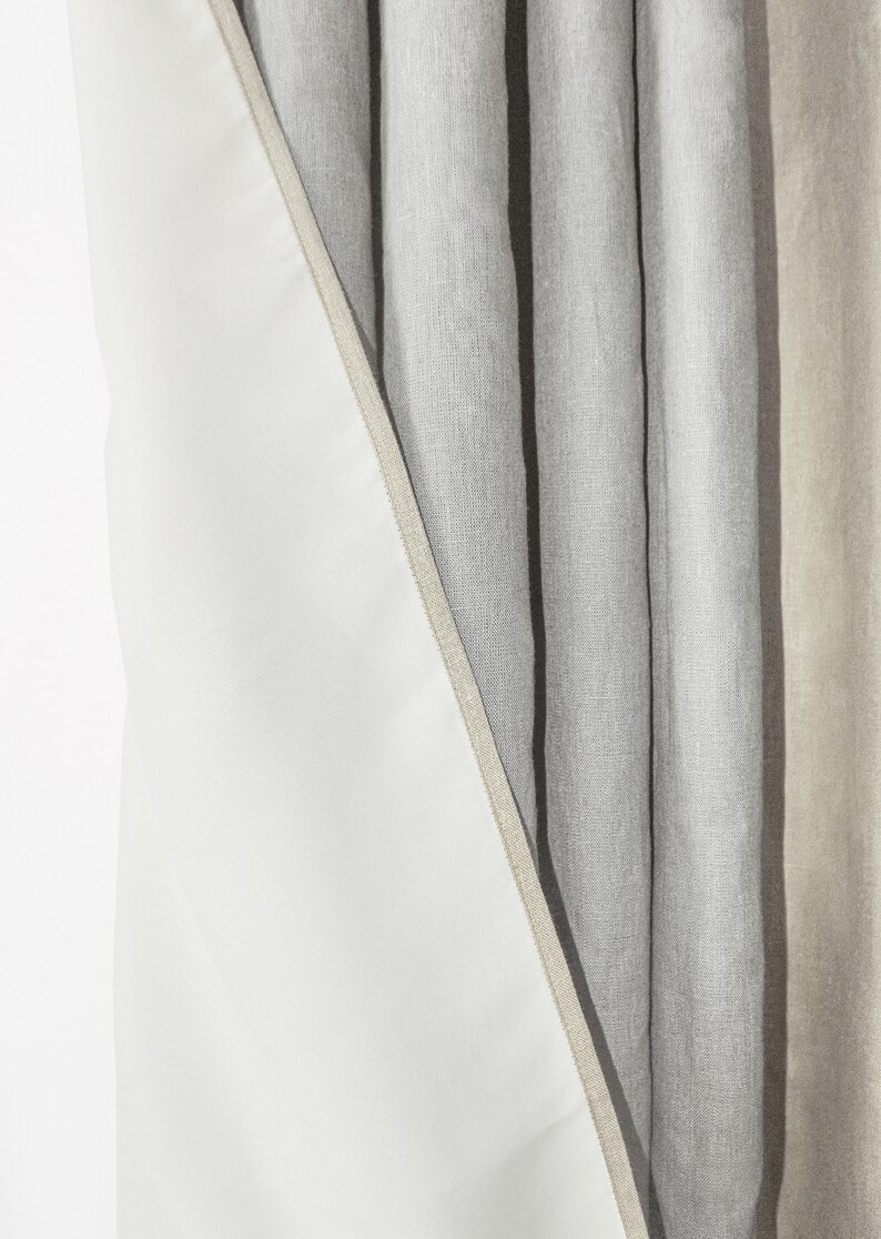 May include: Close-up of a set of linen curtains with a white lining. The curtains are a light gray color and have a subtle texture.