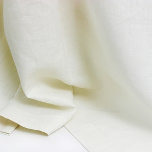May include: A close-up of a white linen fabric, showing its texture and drape.