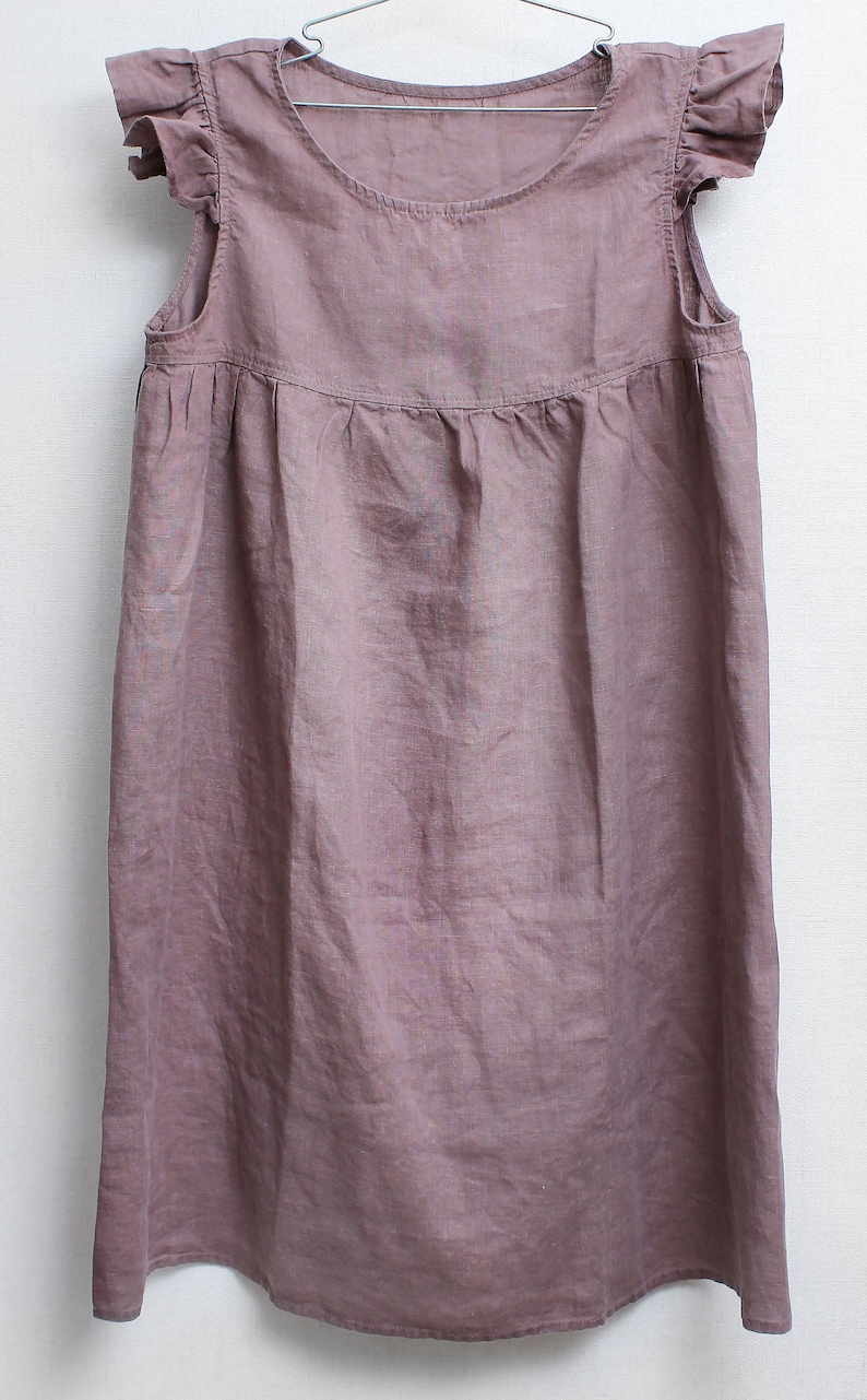 Puede incluir: Un vestido de lino malva con cuello redondo y mangas con volantes.