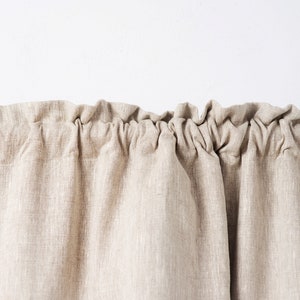 May include: A close-up of a beige linen curtain with a gathered top edge.