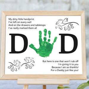Op de afbeelding: Een ingelijst afdruk met een groene handafdruk in het midden, omringd door de letters "D" en "D". De afdruk bevat een gedicht over de handafdrukken van een kind en een boodschap voor een vader. Het gedicht luidt: "Mijn vuile kleine handafdruk Ik heb hem op elke muur achtergelaten En op de lades en tafelbladen Ik heb ze echt allemaal gemarkeerd Maar hier is er een die niet zal uitwissen Ik geef hem aan jou Omdat ik zo dankbaar ben Voor een papa zoals jij!"