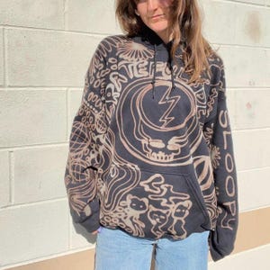 May include: Black hooded sweatshirt with a brown tie-dye pattern featuring a skull and lightning bolt graphic. The text "Grateful Dead" is visible on the front of the sweatshirt.