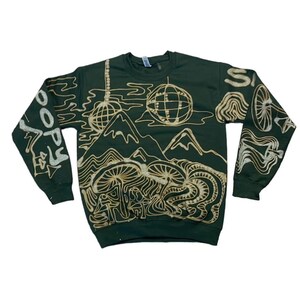 May include: A dark green sweatshirt with a gold design of mountains, mushrooms, and a globe. The text "SOOPY" is on the left sleeve.