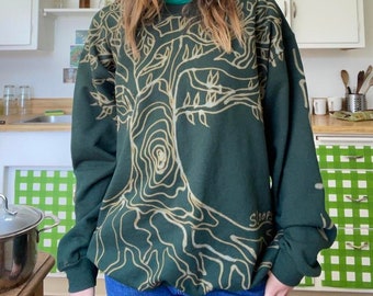 May include: A dark green sweatshirt with a white tree design and the word "slope" printed on the bottom right corner.