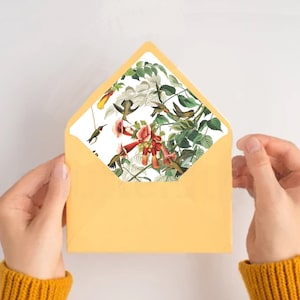 May include: A yellow envelope with a white liner featuring a hummingbird and floral pattern. The liner is visible through the envelope flap.