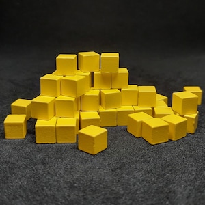 May include: A pile of yellow wooden blocks stacked in a pyramid shape. The blocks are all the same size and shape.