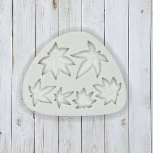 May include: White silicone mold with six leaf shapes. The mold is shaped like a triangle with rounded edges.