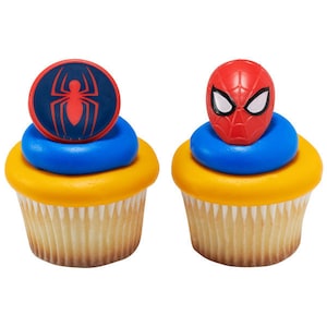 May include: Two yellow and blue cupcakes with red and blue Spiderman toppers. One topper is a Spiderman head and the other is a Spiderman logo.