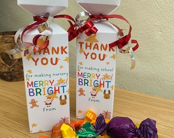 May include: Two white gift boxes with scalloped tops, red ribbon, and the words "THANK YOU" and "MERRY and BRIGHT." Colorful wrapped candies are scattered in front. The boxes are decorated with stars, gingerbread men, and reindeer.