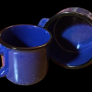 May include: A blue ceramic mug with a black rim and a blue ceramic bowl with a black rim. Both pieces have a speckled finish.