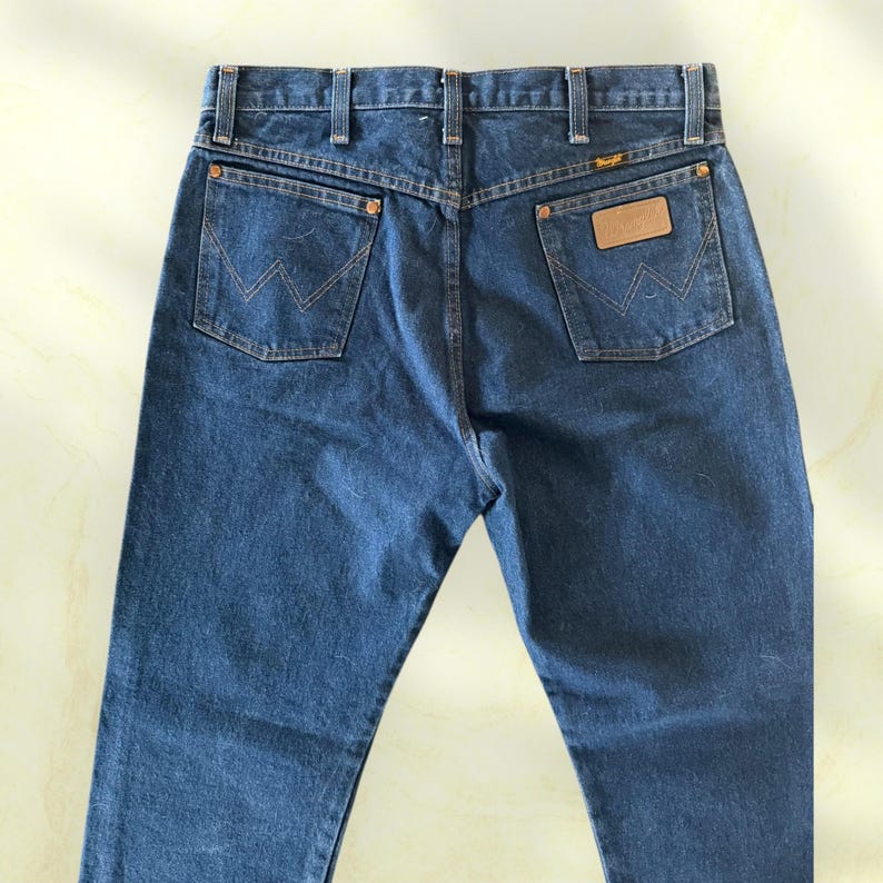 Pu&ograve; includere: Un paio di jeans in denim blu con il logo Wrangler sulla tasca posteriore. I jeans hanno un classico design a cinque tasche, passanti per cintura e chiusura con bottone e cerniera. Le tasche posteriori presentano l'inconfondibile cucitura "W" di Wrangler.