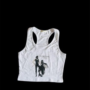 May include: White tank top featuring a black and white image of Fleetwood Mac's "Rumors" album cover.