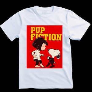 May include: White t-shirt featuring a cartoon graphic on a red background. The graphic depicts a girl and Snoopy, with the text "PUP FICTION" in yellow. The design is a parody of the movie Pulp Fiction.