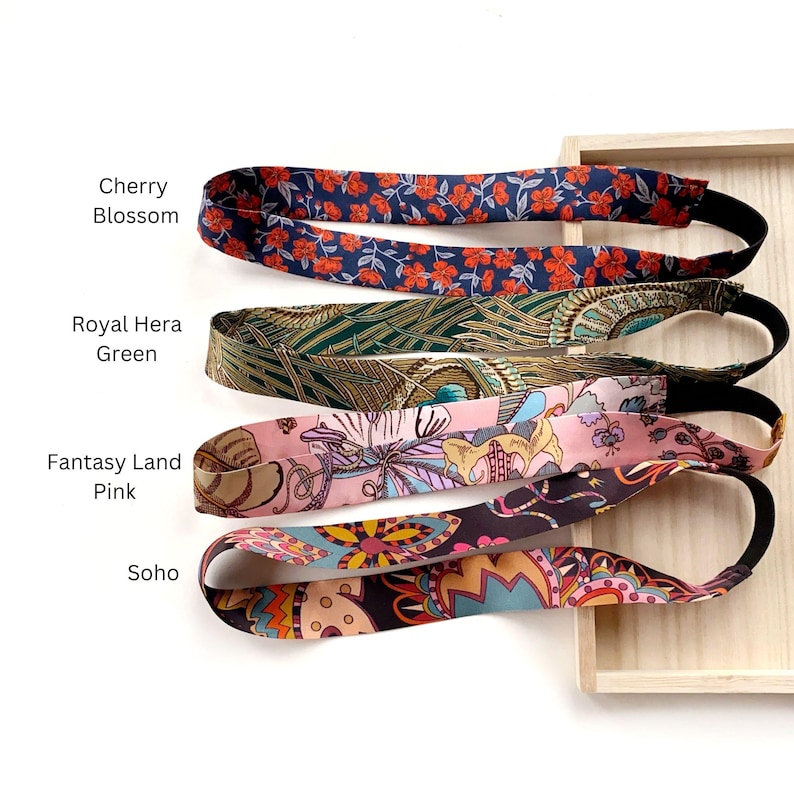 K&ouml;nnte beinhalten: Vier Stoffstirnb&auml;nder mit elastischen R&uuml;ckenb&auml;ndern. Das oberste Stirnband ist marineblau mit roten Kirschbl&uuml;ten. Das zweite ist gr&uuml;n mit einem Pfauenfeder-Muster. Das dritte ist rosa mit einem Blumenmuster. Das unterste ist schwarz mit einem bunten abstrakten Muster.