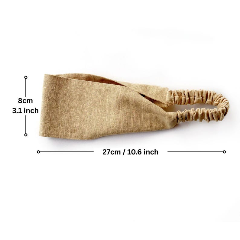 May include: A tan-colored headband with an elastic band. The headband is 10.6 inches long and 3.1 inches wide. The fabric has a textured appearance. The elastic band is gathered and has a similar tan color.