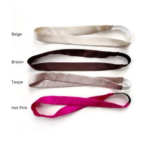 K&ouml;nnte beinhalten: Vier Stirnb&auml;nder aus Satin mit elastischen R&uuml;ckenb&auml;ndern, vertikal angeordnet. Die Farben sind als Beige, Braun, Taupe und Pink gekennzeichnet. Jedes Stirnband hat eine glatte, gl&auml;nzende Oberfl&auml;che und ein flexibles, dehnbares Band.