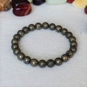 Peut inclure: Un bracelet composé de perles rondes de pyrite gris foncé.