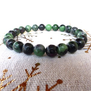 Op de afbeelding: Een groene en zwarte edelsteen armband met ronde kralen. De armband is gemaakt van natuurlijke stenen en is een populaire keuze voor mensen die graag sieraden dragen met een natuurlijke uitstraling.
