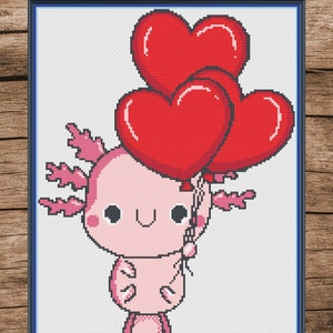 Puede incluir: Un ajolote rosa con una cara linda sostiene tres globos rojos en forma de coraz&oacute;n. El ajolote tiene una cola larga y branquias plumosas.