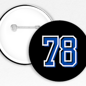 May include: A black and white button with a blue number 78 on it. The number is outlined in white and has a white border around it.