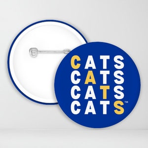 May include: A blue and yellow button with the word "CATS" repeated four times in a vertical stack. The word "CATS" is in white letters with a yellow "C" and "S" in each instance.