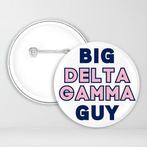 May include: White button with blue text that reads "BIG DELTA GAMMA GUY" with the words "DELTA GAMMA" in pink.