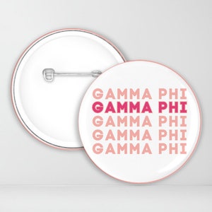 May include: A white button with a pink border and the text "GAMMA PHI" repeated five times in pink and red.