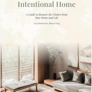 May include: A book cover titled Intentional Home: A Guide to Remove the Clutter from Your Home and Life, Less Distraction, More Living. The background features a light-toned room with a wooden bench, a sofa with grey cushions, and a plant.