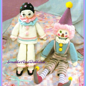 Puede incluir: Dos muñecas payaso de crochet, una con un sombrero rosa y morado y la otra con un sombrero de lunares negros y blancos. Ambas muñecas tienen una cara blanca con rasgos pintados y un cuello de volantes blanco.