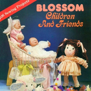 May include: A vintage sewing pattern book cover featuring five handmade dolls. The dolls are a baby in a white crib, a girl with brown hair, a girl with white curly hair, a girl with a halo and pink dress, and a clown doll. The book cover is titled "BLOSSOM Children And Friends" and has a red and white stripe on the top left corner.